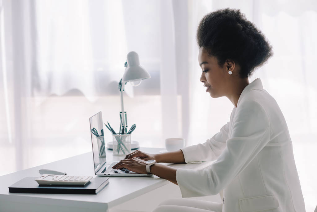 oldalnézetből a vonzó afro-amerikai üzletasszony használ laptop iroda - Fotó, kép