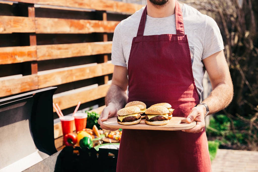 Chef holding board with hamburgers grilled for outdoors barbecue - Photo, Image