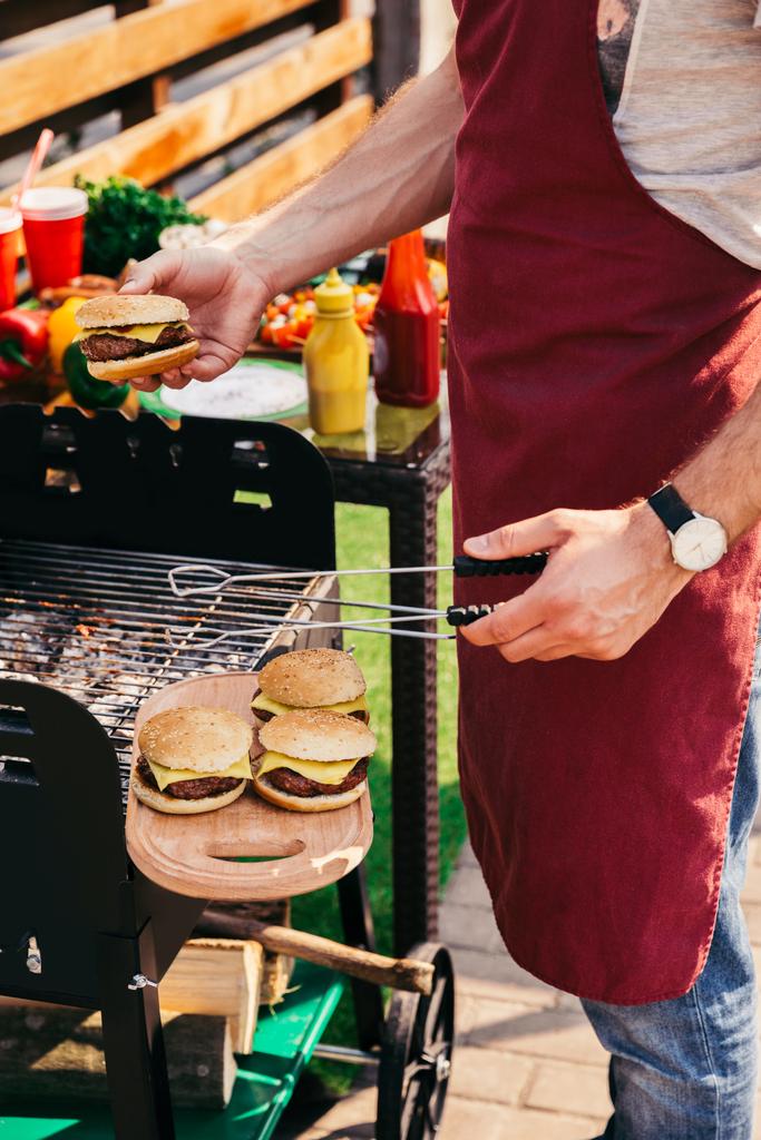 Chef cocinando hamburguesas con queso al aire libre en la parrilla
 - Foto, imagen