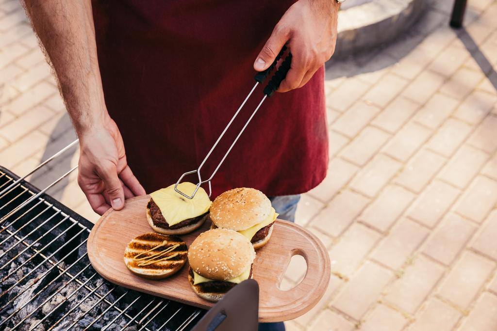 Man serving hamburgers cooked outdoors on grill - Photo, Image