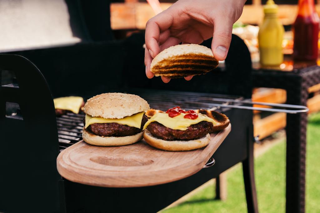 Chef-kok, serveren hamburgers gekookt buitenshuis op een houten bord - Foto, afbeelding