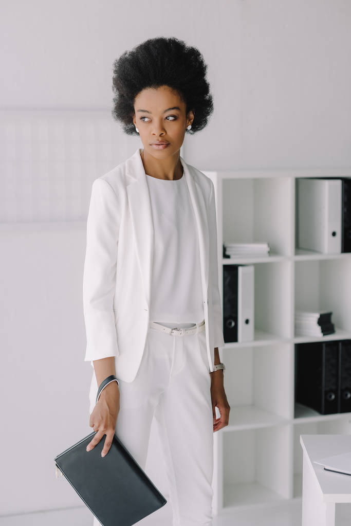 atrakcyjne african american kobieta stojąc z woreczek w biurze - Zdjęcie, obraz