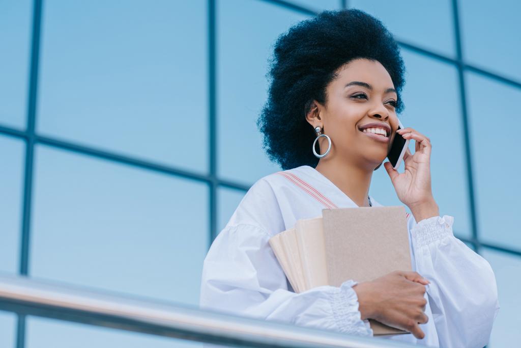 Blick auf eine attraktive afrikanisch-amerikanische Geschäftsfrau, die auf der Straße mit dem Smartphone spricht - Foto, Bild