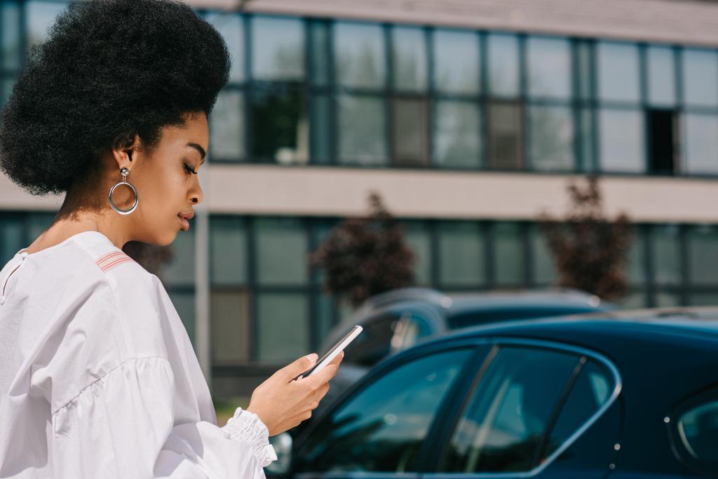 駐車場でスマート フォンを使用して魅力的なアフリカ系アメリカ人実業家の側面図 - 写真・画像