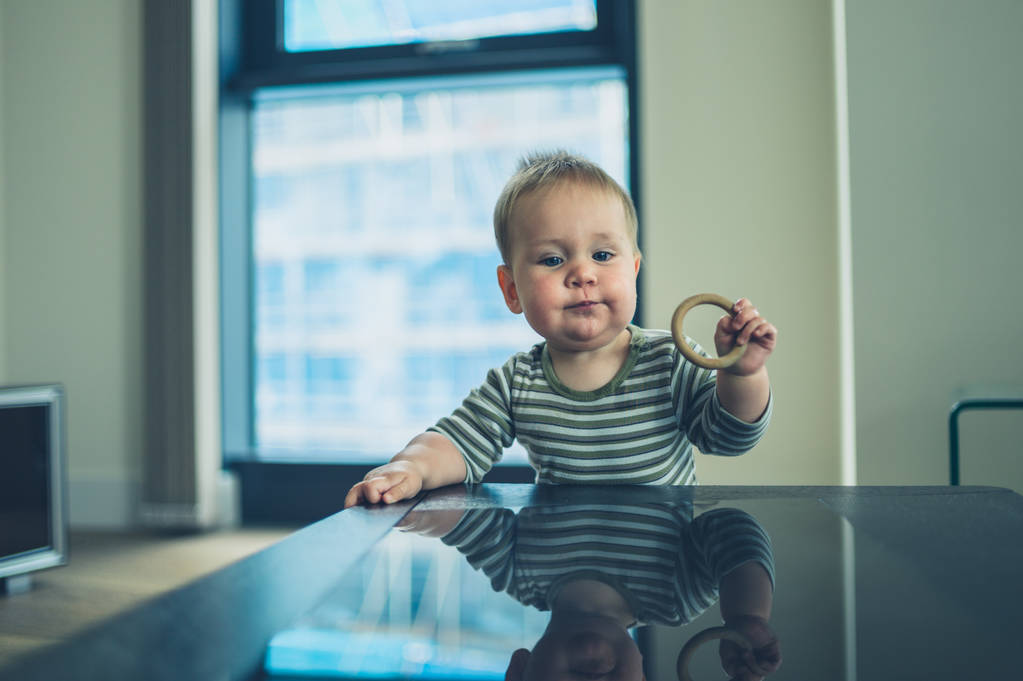 Little baby with teething ring standing at table - Photo, Image