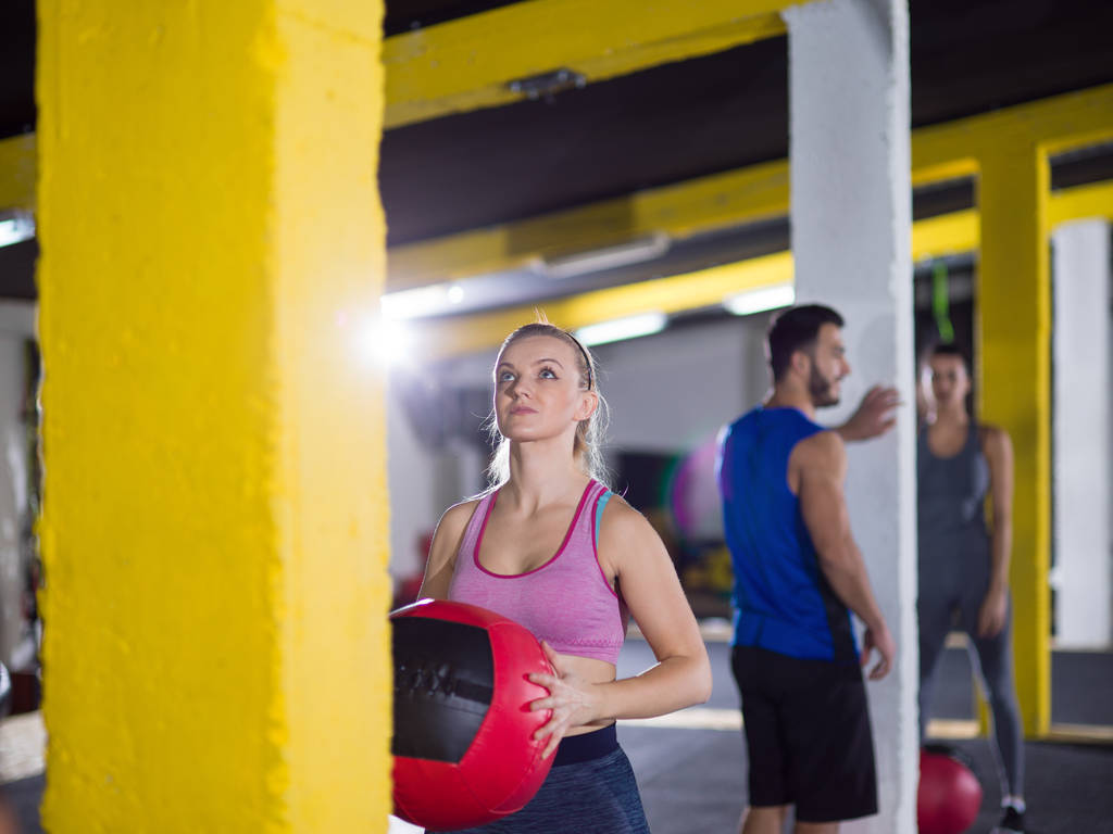 Bir grup genç sporcu sağlık topuyla spor salonunda antrenman yapıyor. - Fotoğraf, Görsel