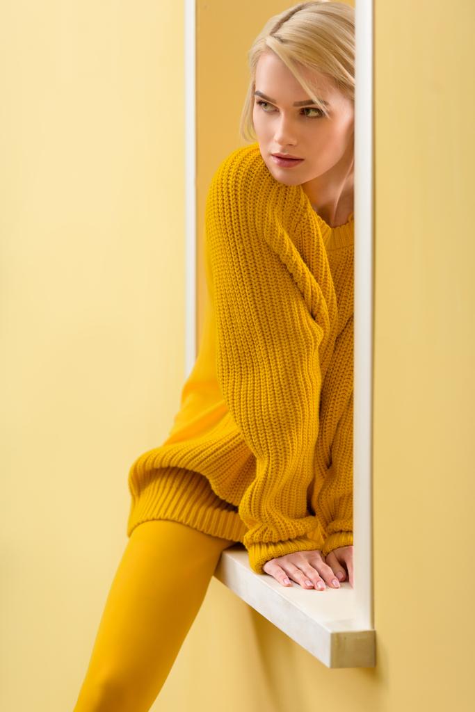 osittainen näkymä tyylikäs mietteliäs nainen keltainen pusero ja sukkahousut istuu koristeellinen ikkuna
 - Valokuva, kuva