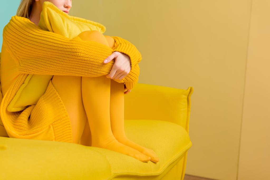 częściowy widok kobiety w żółty sweterek i rajstopy, siedząc na kanapie żółty - Zdjęcie, obraz