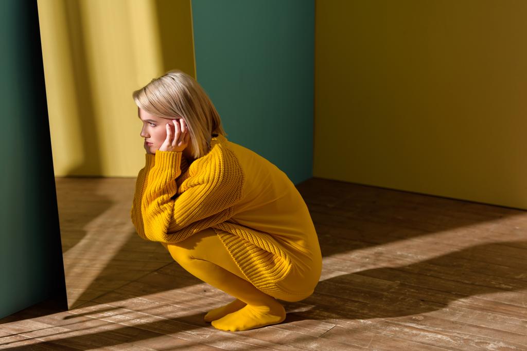 νέοι στυλάτη γυναίκα στον κίτρινο πουλόβερ και καλσόν κάθεται στον καθρέφτη  - Φωτογραφία, εικόνα