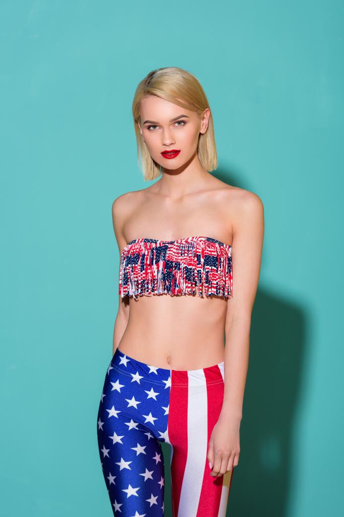 retrato de mujer hermosa en la parte superior y leggings con patrón de bandera americana posando sobre fondo azul
 - Foto, imagen
