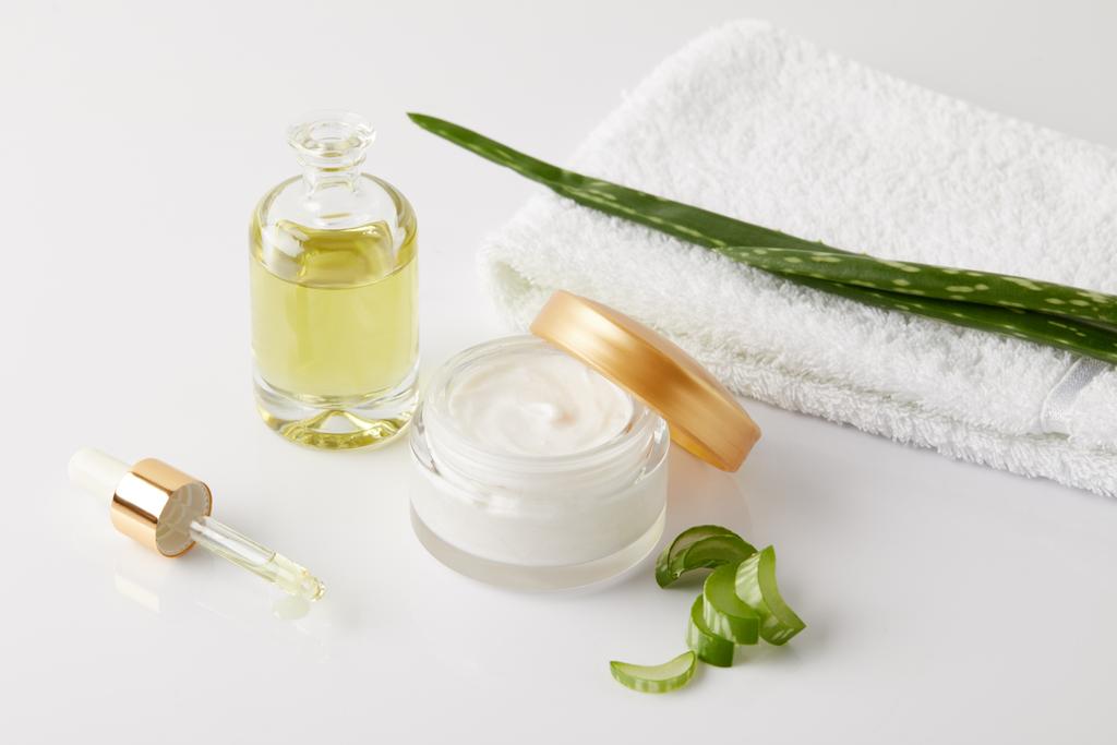 organic cream and perfume, pipette, towel and aloe vera slices and leaf on white surface  - Photo, Image