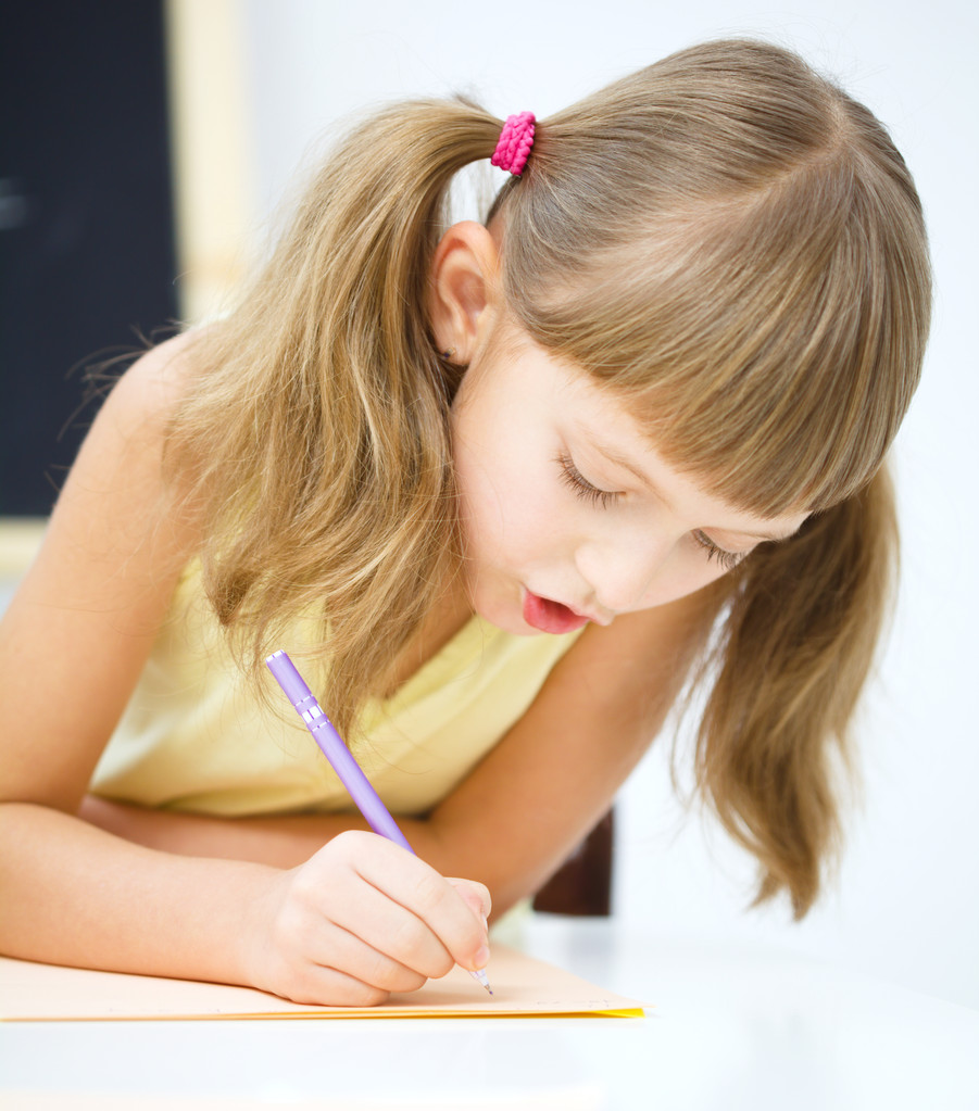 La niña está escribiendo usando un bolígrafo
 - Foto, imagen