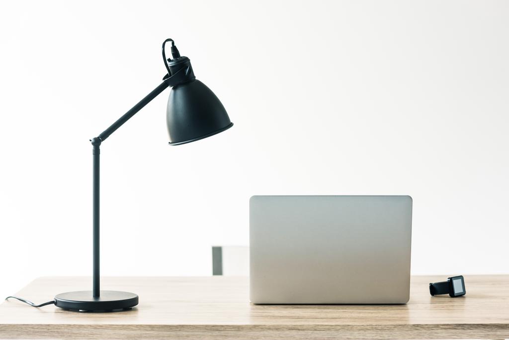 laptop, smartwatch i lampa na drewnianym stole w biurze - Zdjęcie, obraz