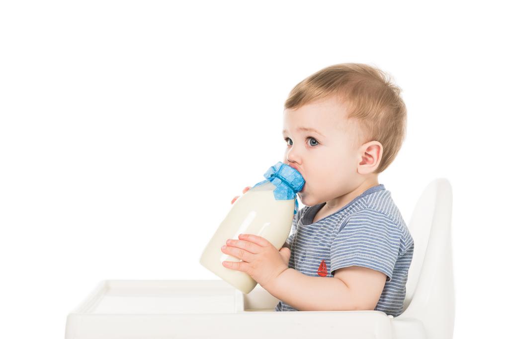 baby boy with bottle of milk and sitting highchair isolated on white background  - Photo, Image