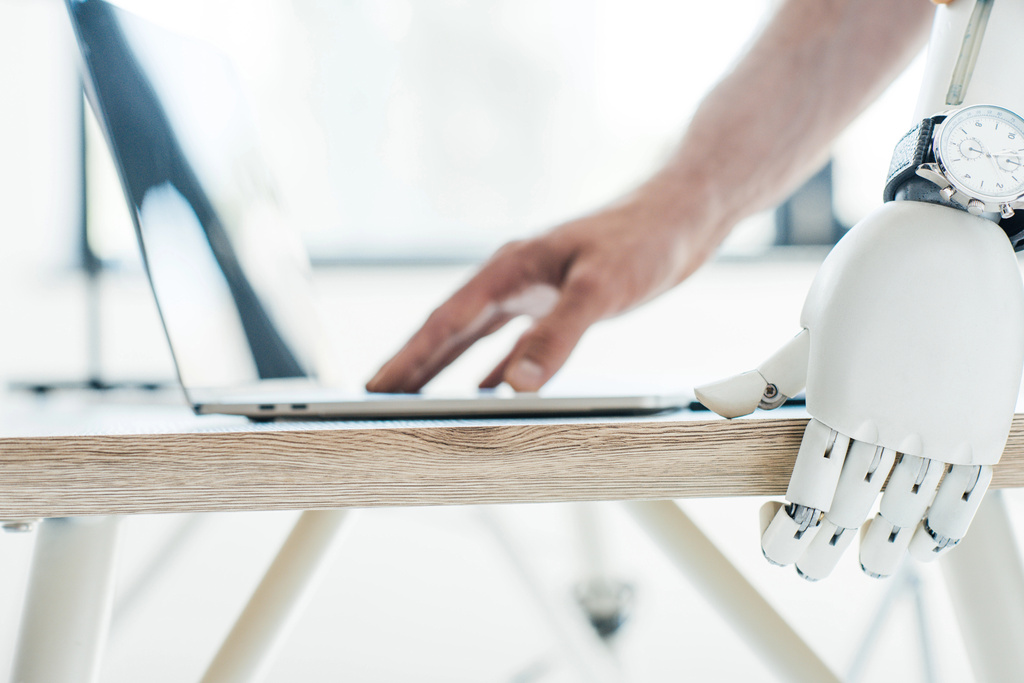 lähikuva robottivarsi rannekellon nojaten puinen pöytä ja ihmisen käsi kannettavan
 - Valokuva, kuva