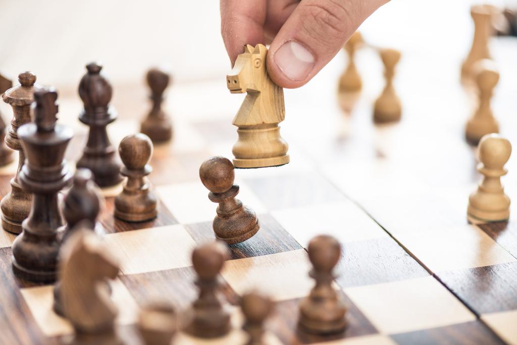 обрезанный снимок человеческой руки, играющей в шахматы, избирательный фокус
 - Фото, изображение