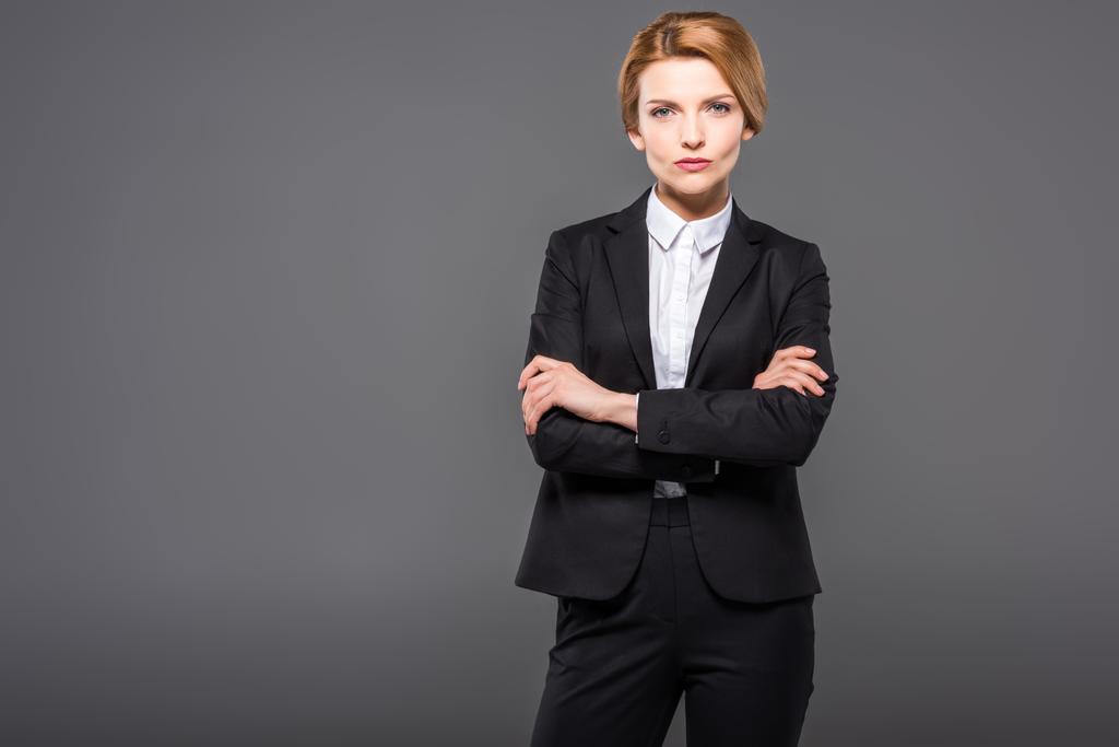 mujer de negocios seria posando en traje con los brazos cruzados, aislado en gris
 - Foto, imagen