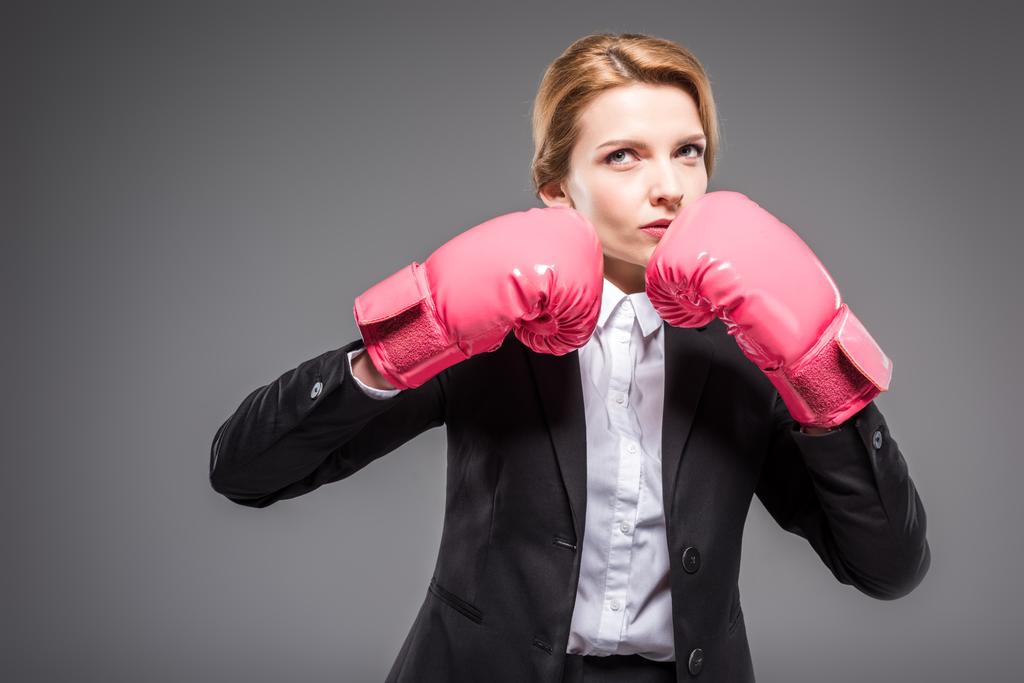 attraente donna d'affari in abito e guanti da boxe rosa, isolato su grigio
 - Foto, immagini