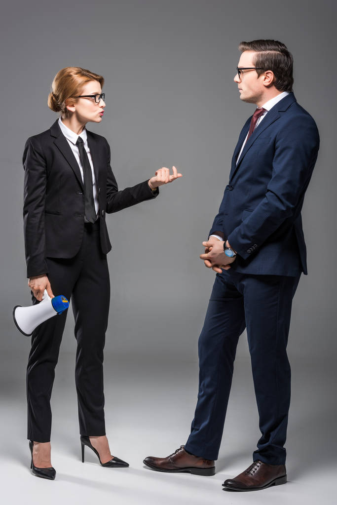Wütende Geschäftsfrau mit Megafon im Gespräch mit Geschäftsmann, isoliert auf grau - Foto, Bild