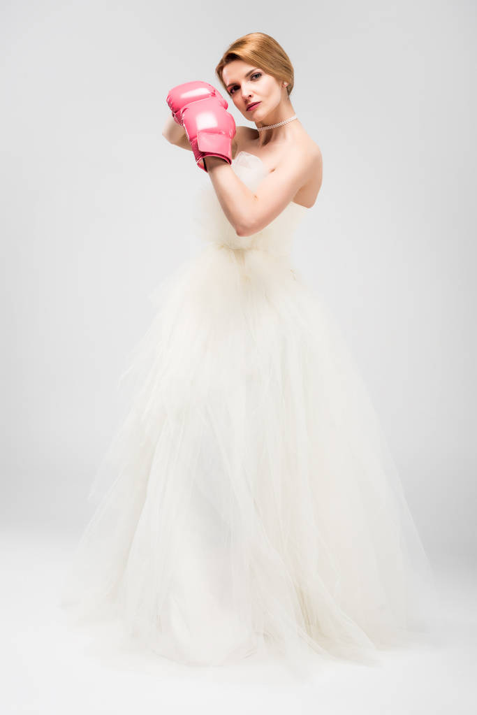 Braut in weißem Hochzeitskleid und Boxhandschuhen, isoliert auf grau, Feminismus-Konzept - Foto, Bild