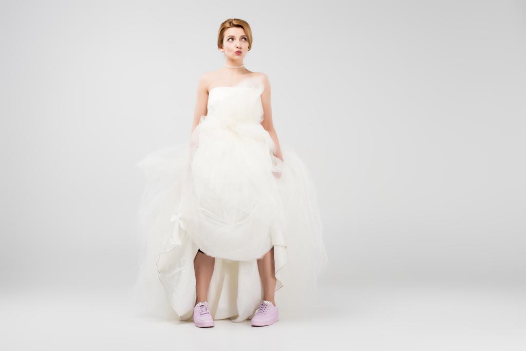 happy bride in white wedding dress and pink sneakers, isolated on grey, feminism concept - Photo, Image