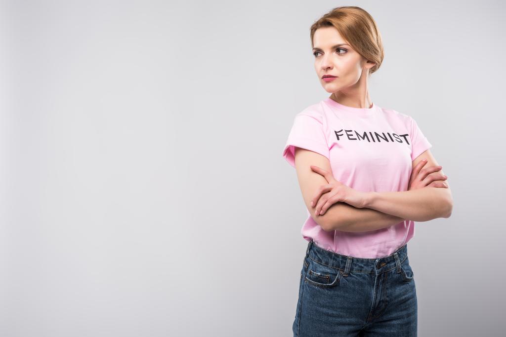 ピンクのフェミニストの女性 t シャツでポーズ組んだ腕、グレーに分離 - 写真・画像