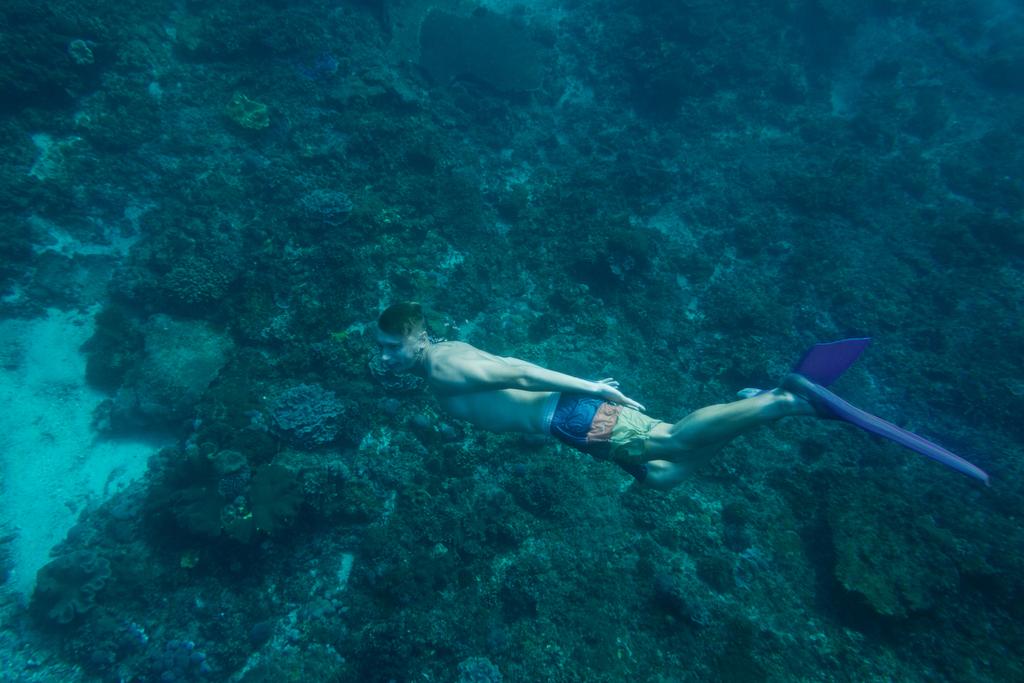 boční pohled na mladíka v ploutve potápění v oceánu sám - Fotografie, Obrázek