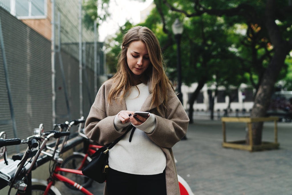 Profi-Blogger mieten Fahrrad per Smartphone-Anwendung, um Staus auf dem Weg zu vermeiden. Hipster-Mädchen tätigt Online-Zahlungsabwicklung per Handy, um die Fahrradmiete zu bezahlen - Foto, Bild