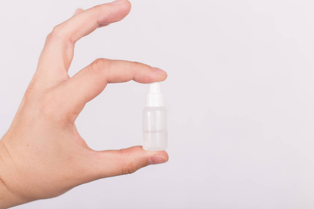 Un petit tube avec un liquide incolore dans une main sur un fond blanc
 - Photo, image