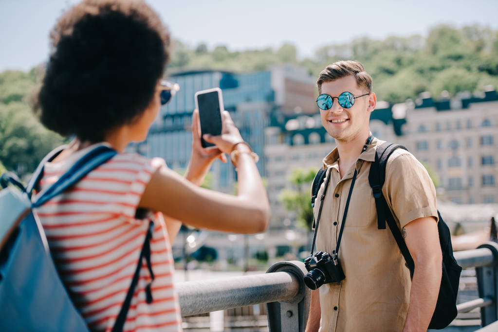 female traveler taking picture of boyfriend on smartphone  - Photo, Image