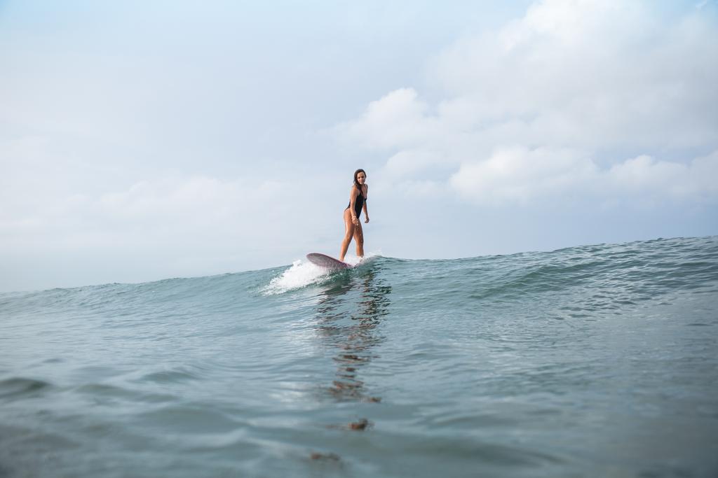 привлекательная молодая женщина стоит на доске для серфинга в океане
 - Фото, изображение