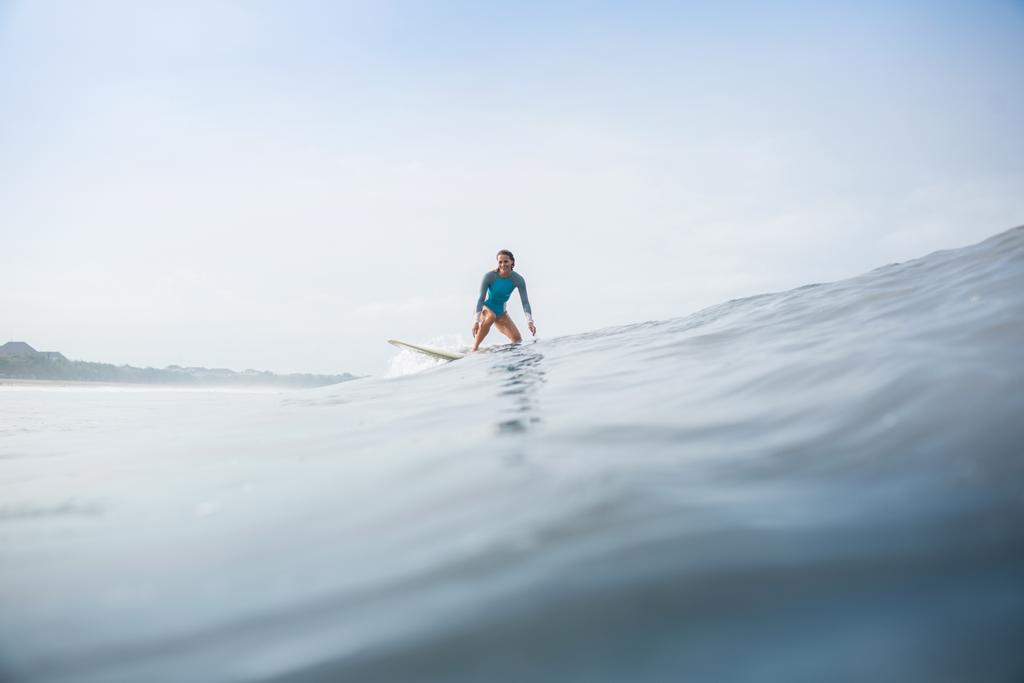 junge Frau im sportlichen Badeanzug reitet Surfbrett im Ozean - Foto, Bild