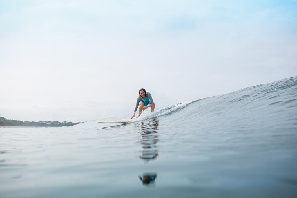 атлетичная молодая женщина в спортивном купальнике катается на доске для серфинга в океане во время летних каникул
 - Фото, изображение