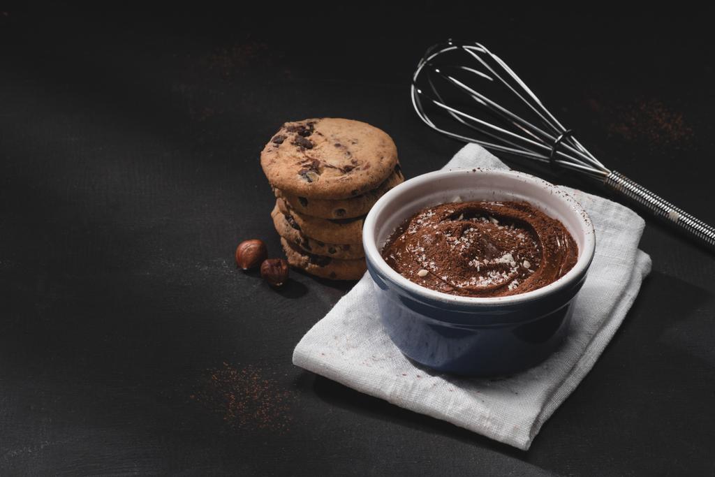 Kom met chocoladedessert, garde en cookies op tafelblad - Foto, afbeelding