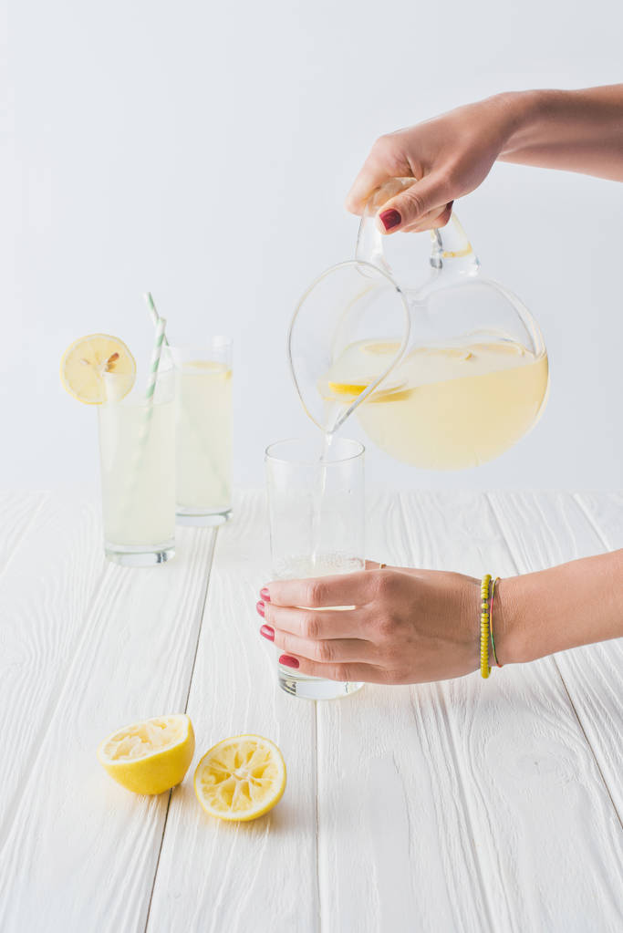 recortado tiro de mujer verter limonada en vidrio sobre fondo gris
 - Foto, Imagen
