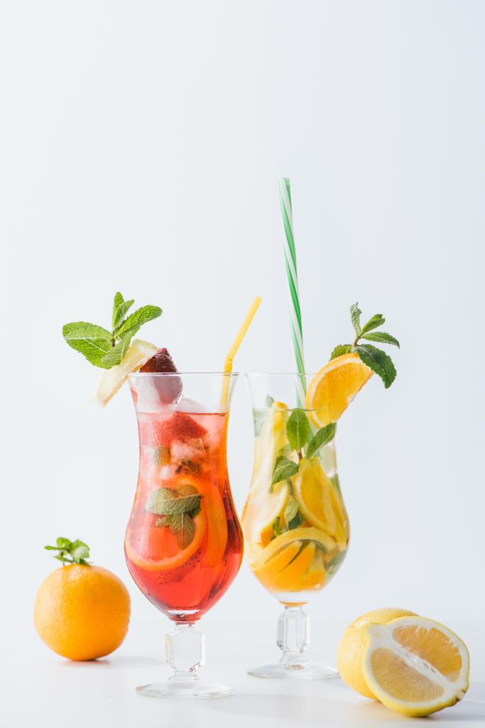 Nahaufnahme von sommerfrischen Cocktails mit Erdbeeren, Zitronen und Orangen, Minze und Strohhalmen isoliert auf weiß - Foto, Bild