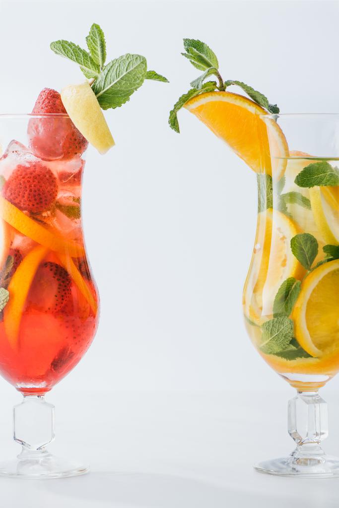 Close-up van zomer verse cocktails met stukjes citroen en sinaasappel, munt geïsoleerd op wit - Foto, afbeelding