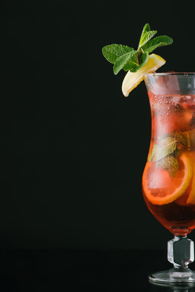 Nahaufnahme von sommerfrischem Cocktail mit Minz-, Zitronen- und Orangenstücken isoliert auf schwarz - Foto, Bild