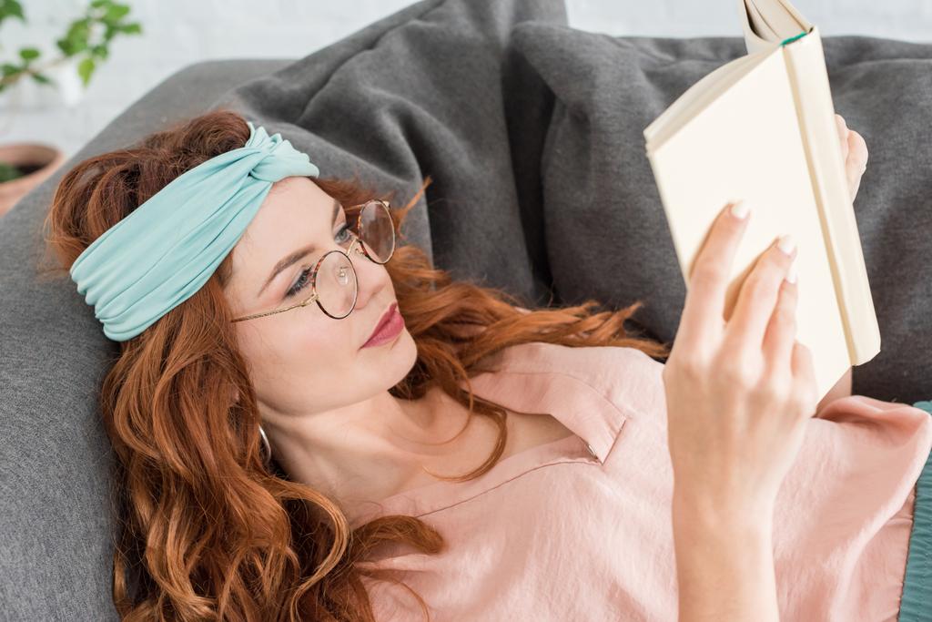 bella giovane donna che legge libro mentre si rilassa sul divano a casa
 - Foto, immagini