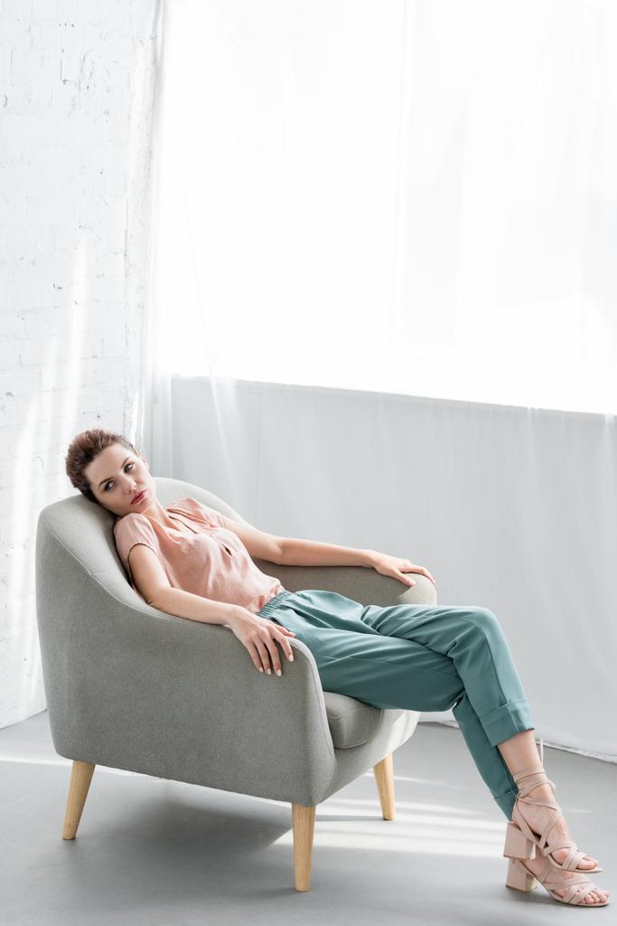 魅力的な若い女性自宅の肘掛け椅子でリラックス - 写真・画像