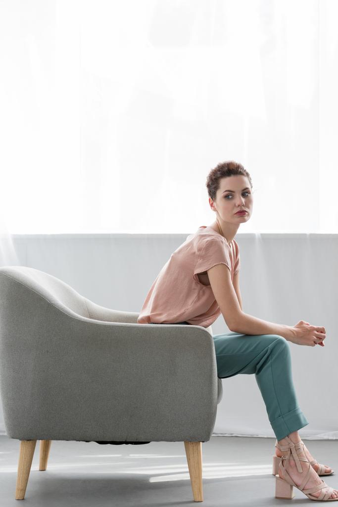 vista laterale di attraente giovane donna seduta sulla poltrona a casa
 - Foto, immagini
