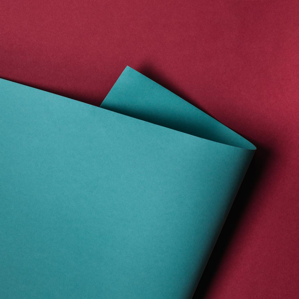 Nahaufnahme eines türkisfarbenen Papierblattes auf kastanienbraunem Hintergrund - Foto, Bild