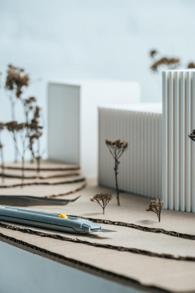 Zobacz artykuły papiernicze nóż i model nowoczesny budynek na stole z bliska - Zdjęcie, obraz