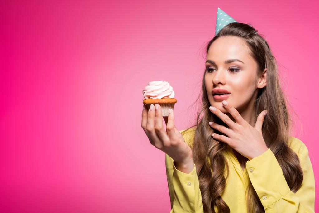 jolie femme avec chapeau de fête tenant cupcake isolé sur rose
 - Photo, image