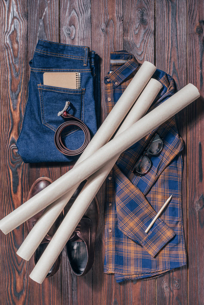 vlakke leggen met mannelijke shirt, schoenen, jeans, brillen en architecturale blauwdrukken die geregeld op houten oppervlak - Foto, afbeelding