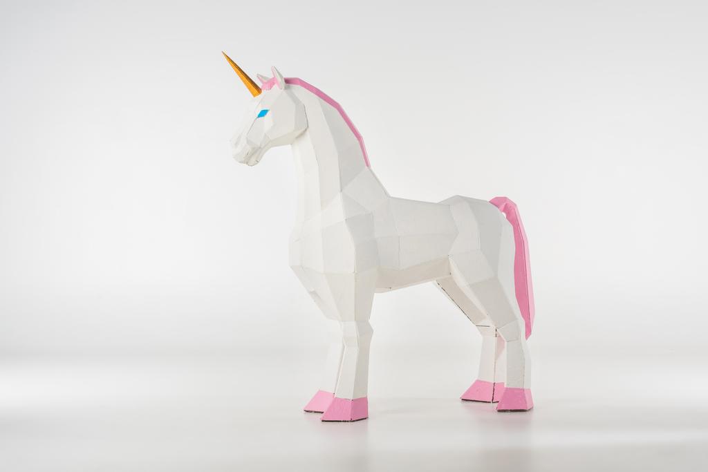 juguete unicornio con cuerno dorado con pezuñas rosadas sobre blanco
 - Foto, imagen