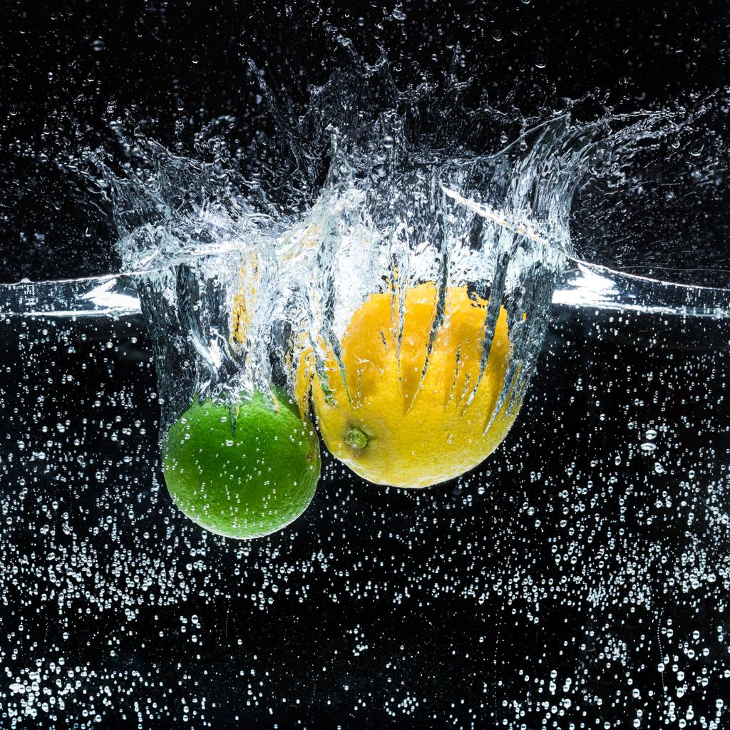 pohled z čerstvé citróny a citrusy ve vodě izolována na černém pozadí na plochu - Fotografie, Obrázek