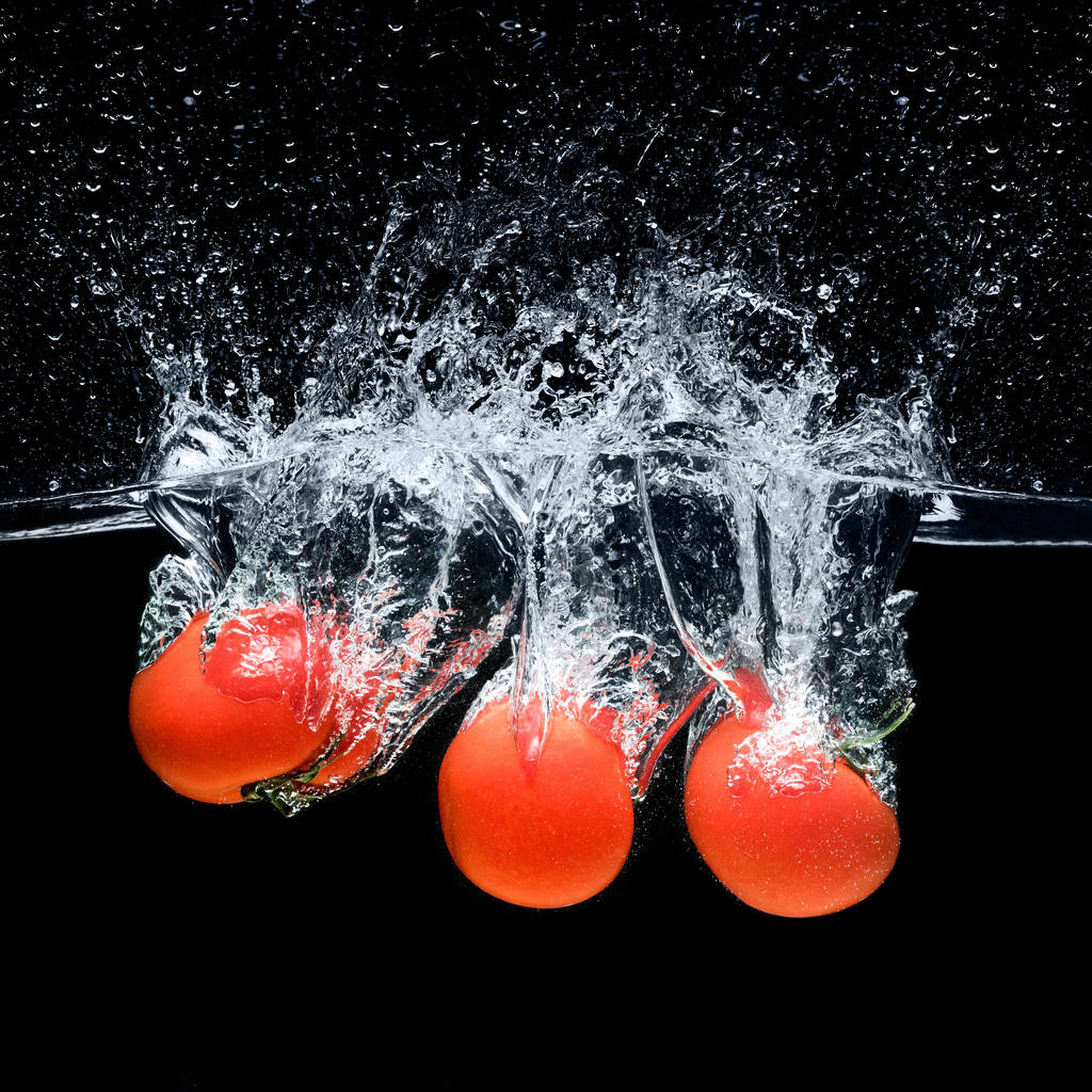 vue rapprochée des tomates mûres tombant dans l'eau isolée sur noir
 - Photo, image