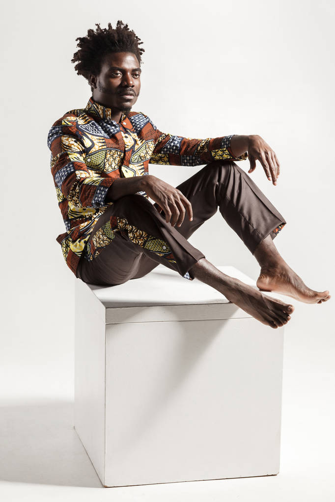 Мода Африканский человек позирует, сидя на кубе изолированы на белом фоне, крупным планом
  - Фото, изображение