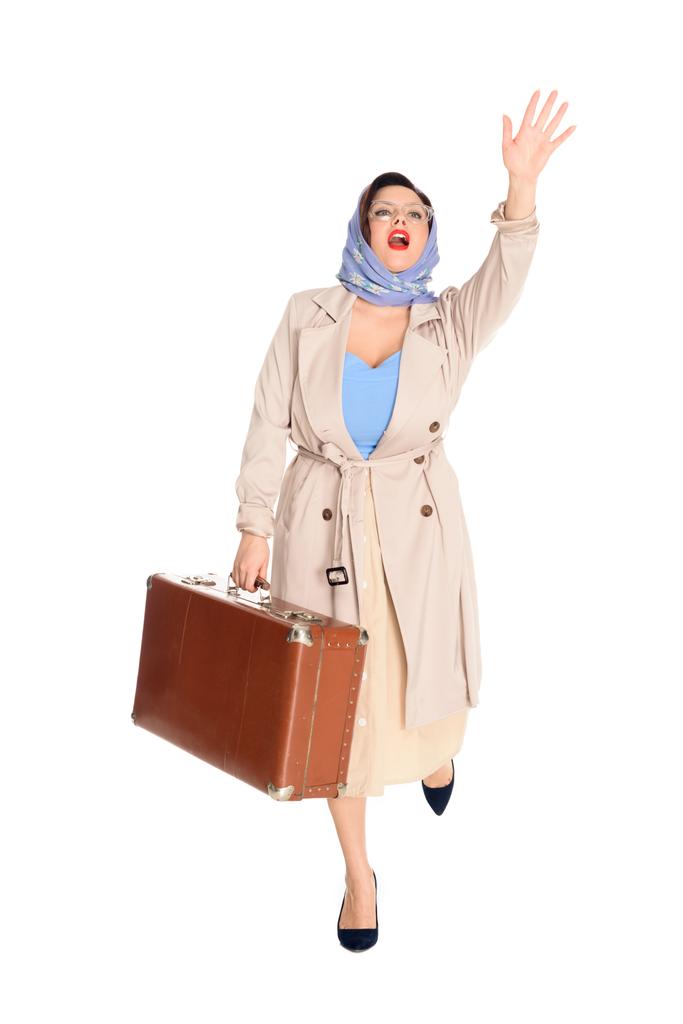 よそ見や白で隔離の手を振ってヴィンテージ スーツケースを持つ若い女性の完全な長さの表示 - 写真・画像